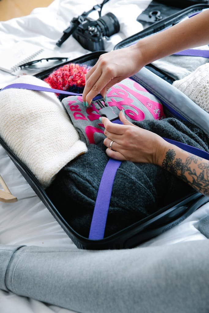 Hands of a Woman Packing Clothes into a Suitcase