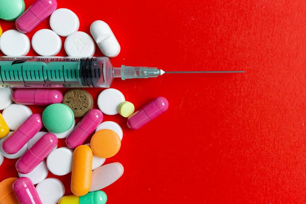 Close-Up Shot of Pills and a Syringe